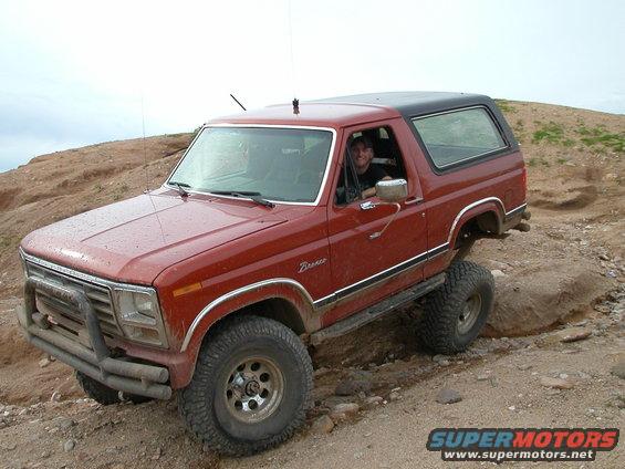 Red Ford Bronco with black top on rocky terrain