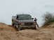1993 Ford Bronco - Ford Ranger pickup truck is shown off-roading on a dirt trail.