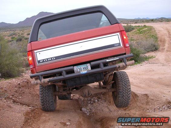 Red 1993 Ford Bronco rear view on dirt trail