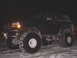 1996 Ford Bronco - A dark 1996 Ford Bronco equipped with oversized tires sits in the snow during nighttime.