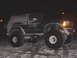 1996 Ford Bronco - Ford Bronco with large tires covered in snow, parked outside at night.