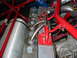 1993 Ford Taurus - Custom exhaust manifold pipes are welded to a radiator assembly, surrounded by red roll cage tubing.