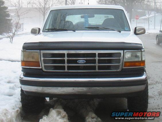 White 1992 Ford Bronco front view in snow, chrome grille, black hood deflector