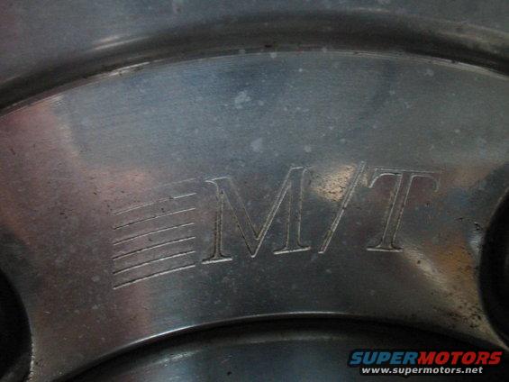 Close-up of a metal wheel with an "MT" logo and horizontal lines