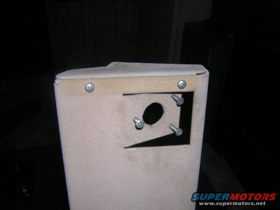 Close-up of a beige speaker enclosure with four screws visible around a cutout hole