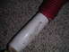 1994 Ford Bronco - A close-up view of a shock absorber with red bellows rests on a carpeted surface.