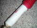 1994 Ford Bronco - A white and red shock absorber is shown against a carpeted background.
