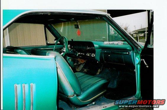 Green vinyl interior of a 1967 Pontiac LeMans convertible, showing the dashboard, steering wheel, and front seats