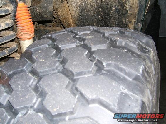 Close-up of a large, knobby tire with an orange shock absorber and coil spring visible