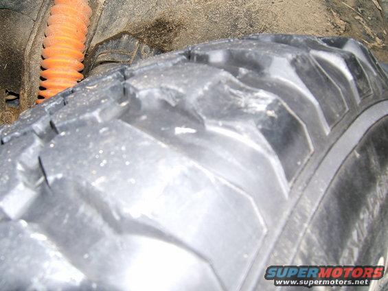 Close-up of a knobby off-road tire and orange shock absorber