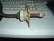 1989 Ford Escort - A close-up view of a rusty automotive part with white plastic and brass components.