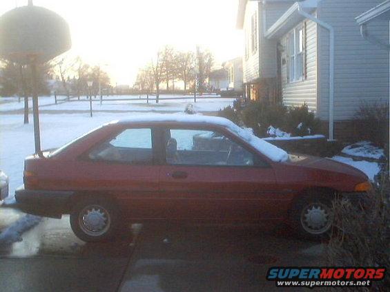 red coupe parked in driveway with snow on the ground and on the car