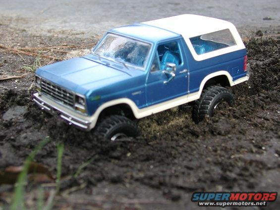 Blue and white toy SUV stuck in mud, front grille visible