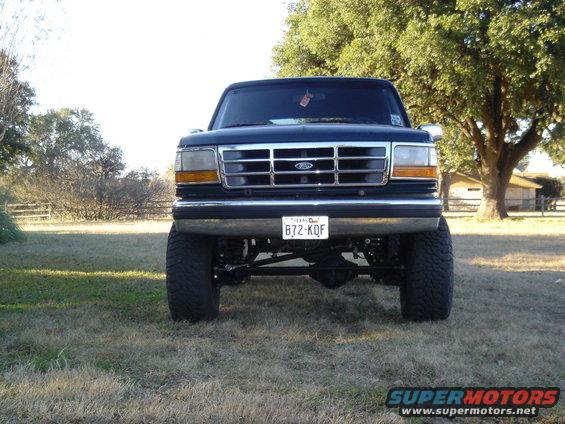 Front view of a dark blue 1995 Ford Bronco with a chrome grille and lifted suspension