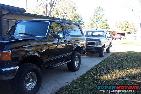 Black 1989 Ford Bronco in foreground, white 1989 Ford Bronco behind it