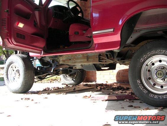 Red SUV, driver's side door open, showing interior and lifted chassis with large tires