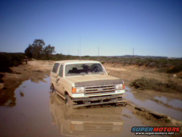 Tan 1990 Ford Bronco stuck in mud, front 3/4 view