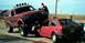 1982 Ford Bronco - A red pickup truck is precariously balanced on top of a red hatchback car.