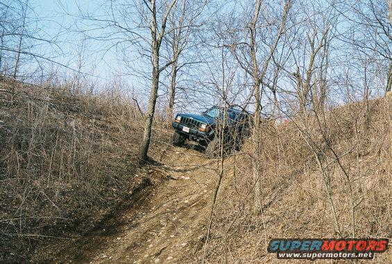 Dark green Jeep Cherokee climbing a steep, wooded hill