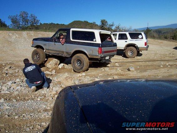 Two-tone gray and black Ford Bronco with lifted suspension on rocky terrain