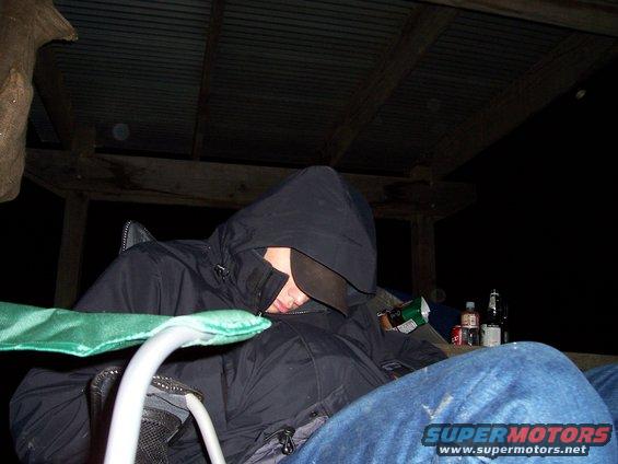person in a hooded jacket sleeping in a chair