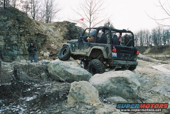 Black Jeep Wrangler TJ navigating large rocks on an off-road trail