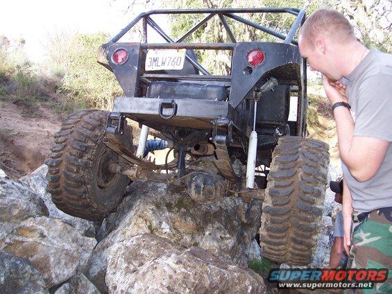 Off-road vehicle with large tires navigating rocky terrain. License plate reads 3MLW760