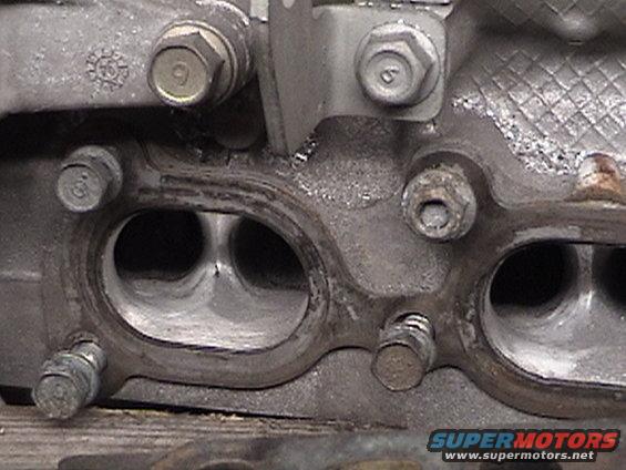 Engine cylinder head with intake ports visible, showing bolt heads and gasket residue