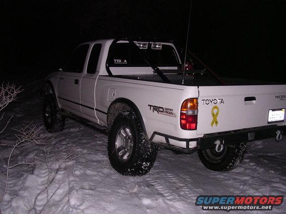 White 1999 Toyota Tacoma parked in snow at night. Has TRD Off Road decal and yellow ribbon sticker on tailgate