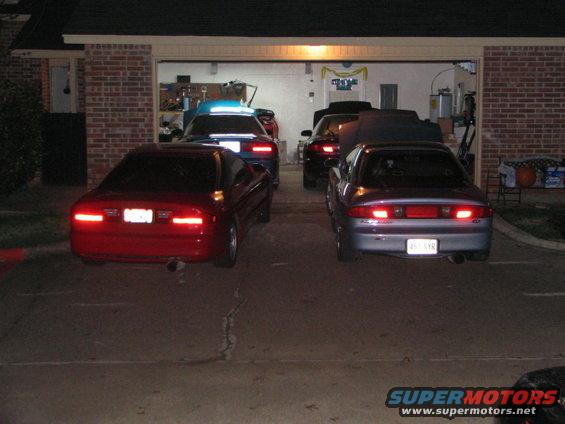 Four cars parked in front of a garage at night