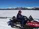 1994 Ford Bronco - A person rides a red Polaris snowmobile across a snowy landscape with mountains in the background.