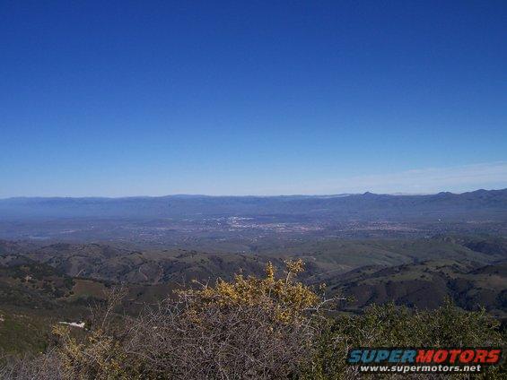 view of a valley and distant mountains under a clear blue sky