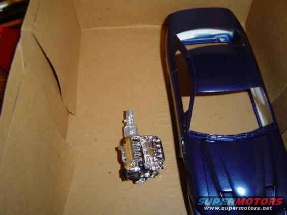 Model car engine and blue body in cardboard box