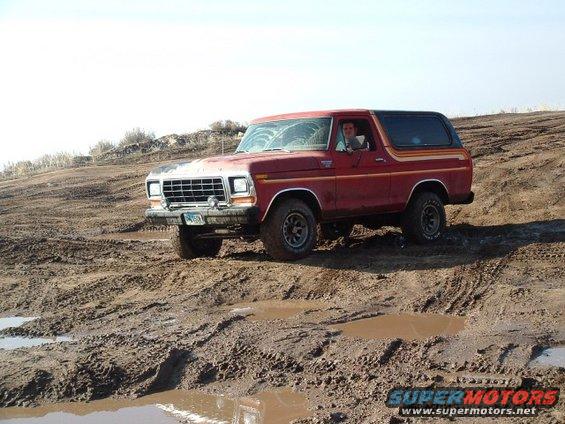 Red 1978 Ford Bronco in mud, 3q-front view