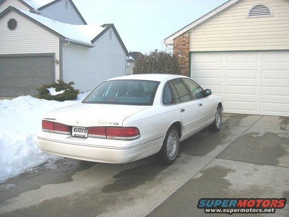 White 1997 Ford Crown Victoria parked in a driveway with snow on the ground