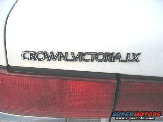 Crown Victoria LX badge on white car trunk near red taillight