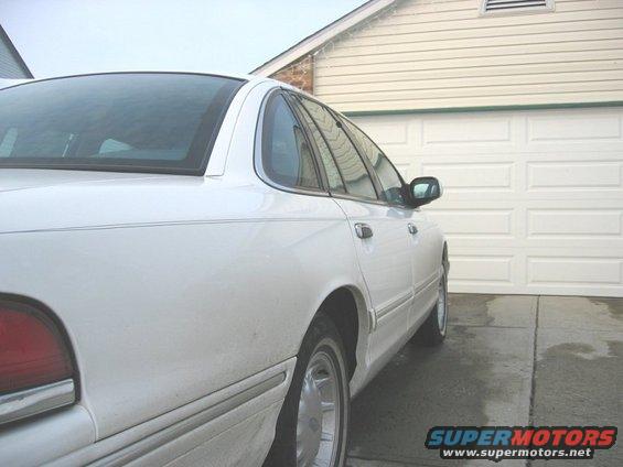 1997 Ford Crown Victoria parked on wet concrete in front of a white garage door