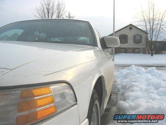White sedan parked next to a snowbank, house in background