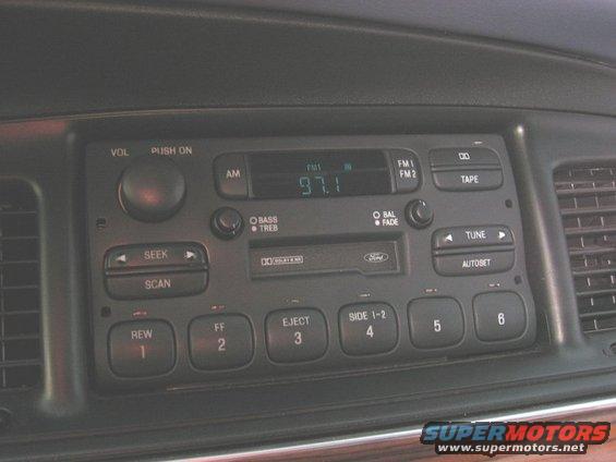 Dashboard view of a car's radio with cassette player and digital tuner showing 97.1 FM