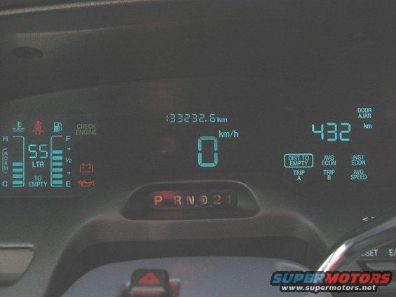 Car dashboard with digital speedometer showing 0 km/h, fuel gauge, odometer reading 133232.6 km, and gear selector P R N D 2 1