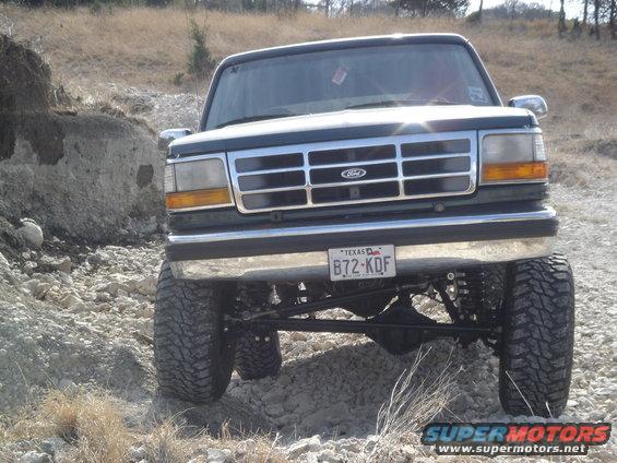 1995 Ford Bronco front view, lifted with large tires, on a rocky, off-road trail