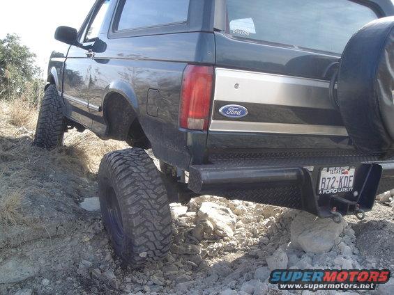 Ford Bronco on rocky terrain, rear view. It has large tires and a spare tire on the back