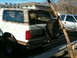 1996 Ford Bronco - Rear view of a white 1996 Ford Bronco, a spare tire mounted on the tailgate and a white pickup truck in the background.