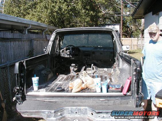 Interior of disassembled 1980s pickup truck bed and cab with trash and drinks
