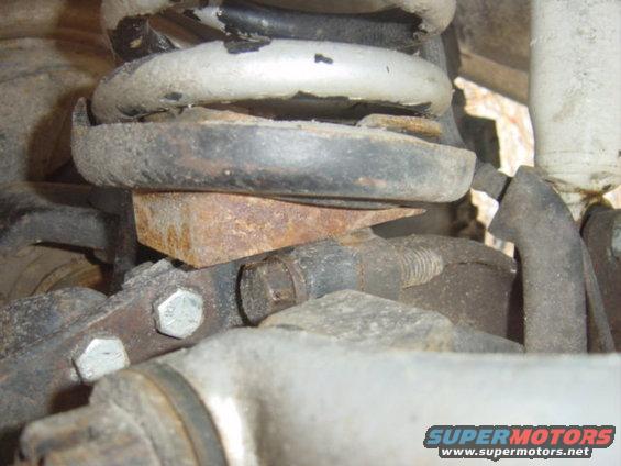 Close-up of rusty metal parts and a coil spring in a vehicle's suspension system