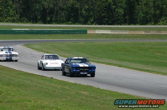 1965 Ford Mustang and two other race cars on a track