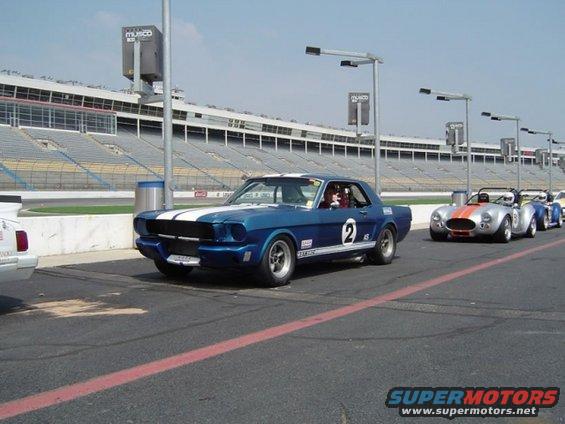 Blue 1965 Ford Mustang race car with white stripes and number 2 on track