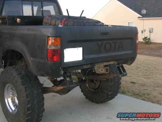 Black Toyota pickup truck's rear with a spare tire in the bed and a tow hitch