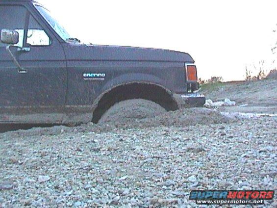 Dark 1989 Ford Bronco stuck in mud, side view