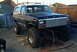1986 Ford Bronco - This lifted 1986 Ford Bronco features a black body with a white roof and prominent off-road tires.